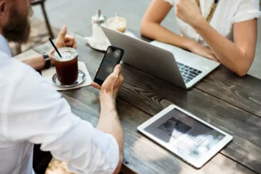 Descubra 9 ferramentas de otimização gratuitas para melhorar sua produtividade profissional. Imagem de pessoas usando dispositivos em um ambiente de trabalho.