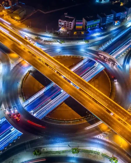 Imagem de uma rodovia urbana iluminada à noite, com sobreposição de faixas de luz de veículos em movimento, ilustrando o conceito de fator multiplicador para infrações gravíssimas (x3, x5, x10, até x60).