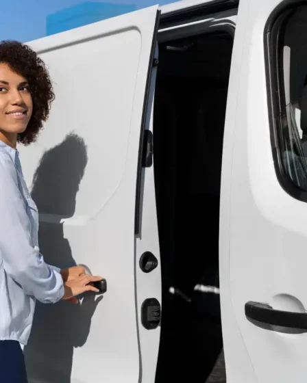 Mulher sorridente preparando van branca para transporte de convidados em evento, destacando a locação de van para transporte de convidados com conforto e logística inteligente.