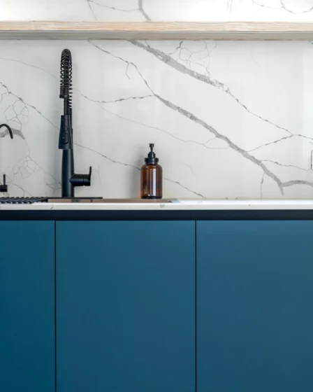 Imagem de uma cozinha moderna com cuba e torneira preta, bancada branca e portas de armário de PVC azul, ideal para quem busca como escolher porta de PVC para armário de pia
