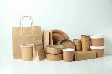 Diversos embalagens alimentícias de papel e plástico, incluindo copos, caixas e sacolas, representando o mercado que abastece restaurantes.