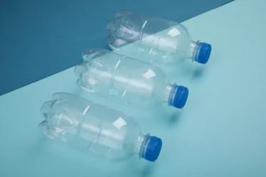 Imagem de três garrafas PET transparentes, destacando sua preferência entre os consumidores, com fundo azul e uma composição que evidencia o uso do produto.