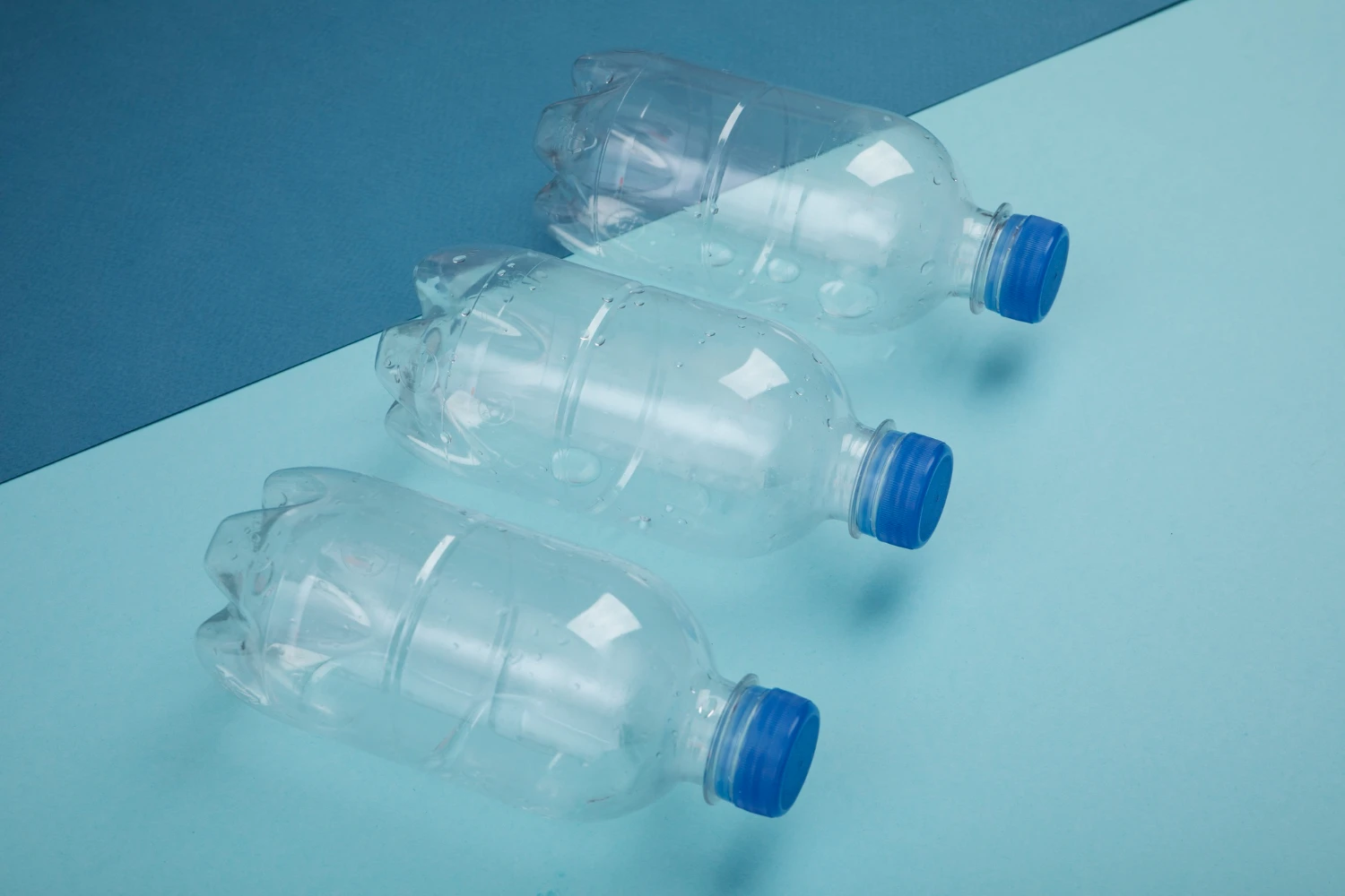 Imagem de três garrafas PET transparentes, destacando sua preferência entre os consumidores, com fundo azul e uma composição que evidencia o uso do produto.