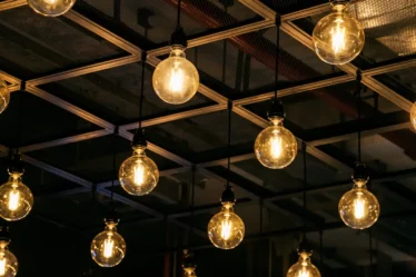 Iluminação estilo Industrial: Pendentes, trilhos e lâmpadas que fazem a diferença: Iluminação estilo Industrial: Pendentes, trilhos e lâmpadas com design em vidro e filamento exposto, penduradas em estrutura metálica quadriculada, criando efeito acolhedor em ambiente interno.