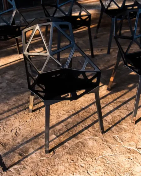 Móveis de estilo Industrial: Como escolher peças de metal e madeira de demolição: Conjunto de cadeiras e mesas com estrutura de metal em design geométrico, apoiadas sobre piso de concreto queimado, estilo industrial com aparência robusta.