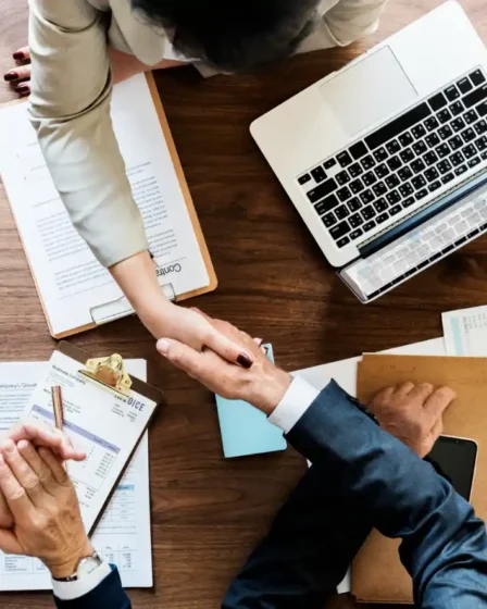 Self-Attribution: Como Implementar uma Pesquisa Simples para Descobrir Como o Cliente Realmente Chegou Até a Marca: Profissionais analisando relatórios e planilhas em uma mesa de escritório, com um notebook e gráficos abertos durante reunião para discutir dados de marketing e clientes.